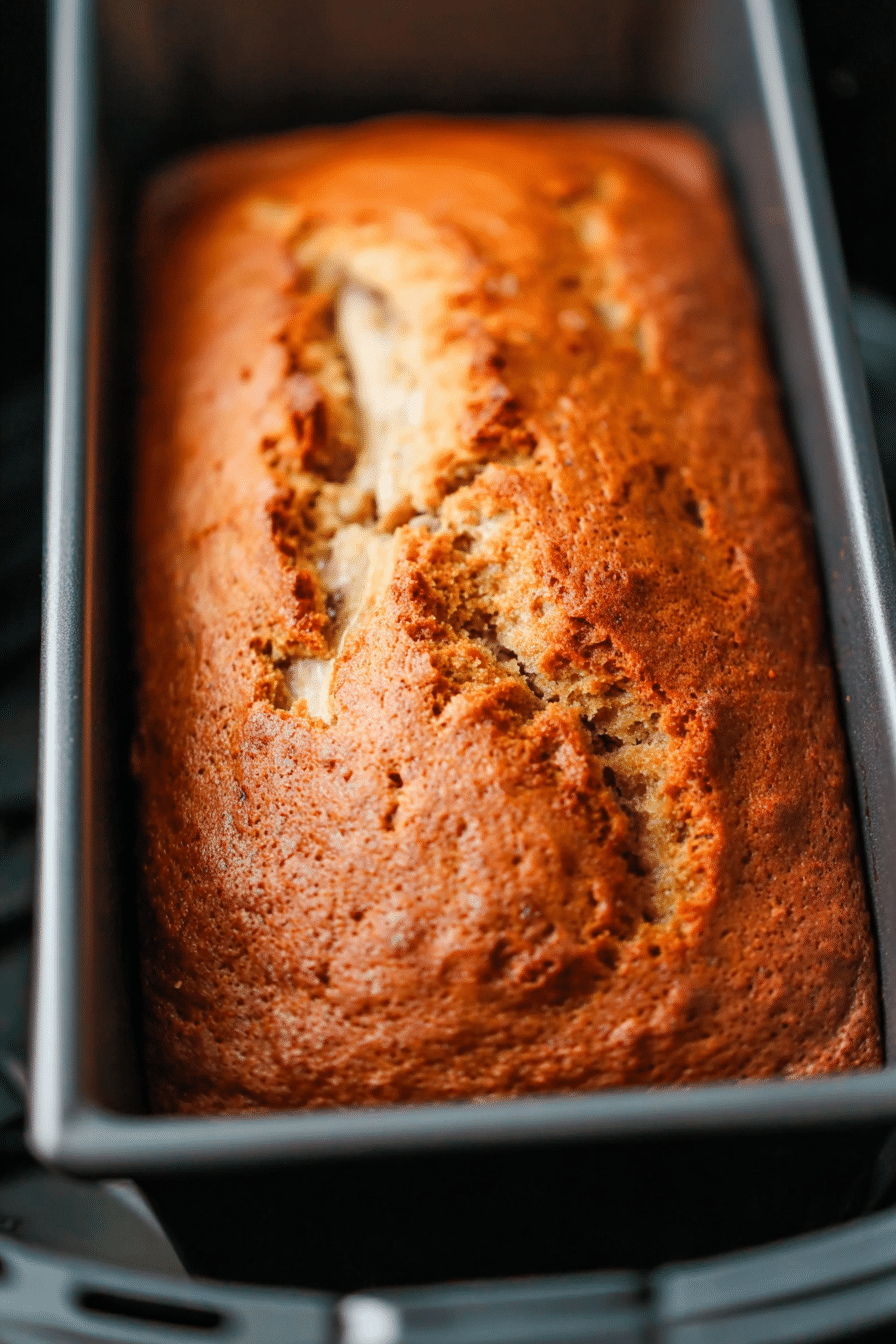 Air fryer banana bread loaf with golden crust in baking pan