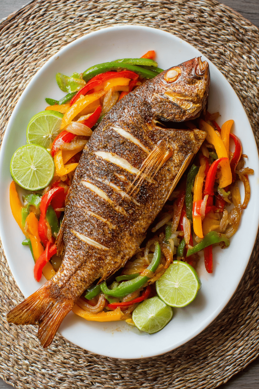 Air fryer whole snapper with crispy golden skin served with bell peppers, onions, and lime