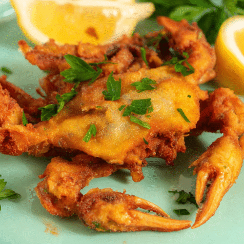 Golden crispy air fryer soft shell crab garnished with parsley and served with lemon wedges