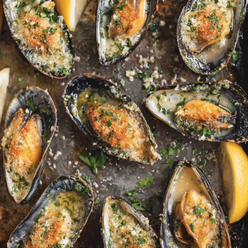 Air fryer garlic butter mussels baked with herbs, breadcrumbs, and lemon wedges